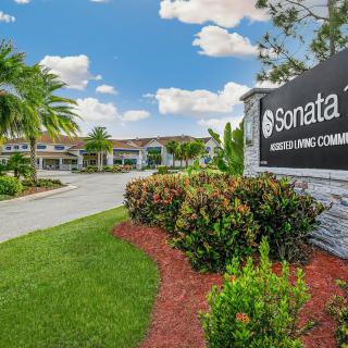 Entrance to a building complex with landscaped greenery and clear skies.