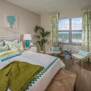 A bright and airy coastal-themed bedroom with vibrant decor and ocean view.