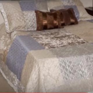 A neatly made bed with a patchwork quilt and decorative pillows.