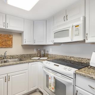 A modern kitchen with white cabinets and granite countertops.