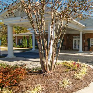 A well-maintained building entrance with surrounding trees and shrubs.