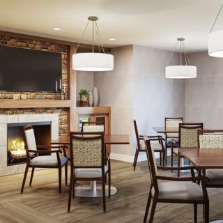 A modern dining room with a cozy fireplace, featuring wooden tables and chairs under soft pendant lighting.