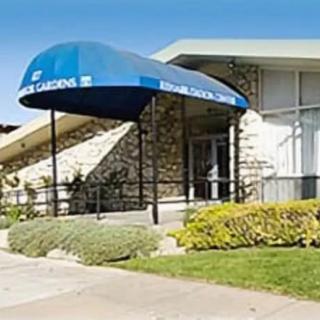 A building entrance with a blue awning and landscaped area.