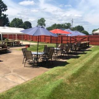 An outdoor patio area with tables and umbrellas on a sunny day.