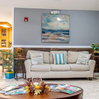 A cozy living room featuring a comfortable sofa, decorative artwork, and a stylish coffee table adorned with magazines and flowers.