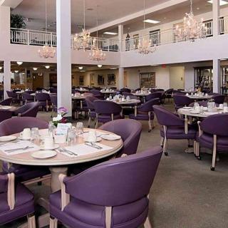 A spacious and elegantly decorated restaurant dining area with purple chairs and chandeliers.