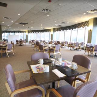 An empty restaurant dining area with neatly arranged tables and chairs, featuring large windows.