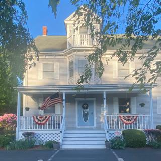 A charming white house adorned with patriotic flags and surrounded by a well-kept garden.