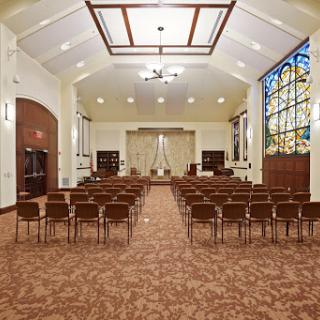 A serene interior view of a chapel featuring rows of chairs and a beautiful stained glass window.