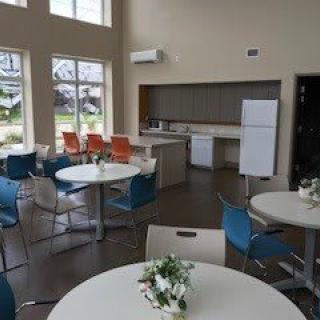 A modern dining and kitchen area with colorful chairs and a large refrigerator.