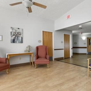 A cozy waiting area with wooden flooring, armchairs, a ceiling fan, and decorative elements.