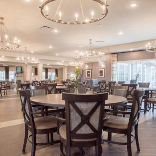 A spacious and elegantly designed dining area featuring round tables and chandeliers.
