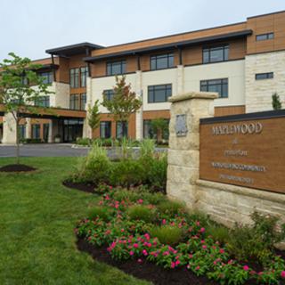 An exterior view of a modern building with well-maintained landscaping and a prominent entrance sign.