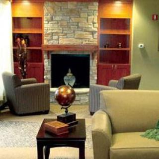 A cozy living room featuring comfortable seating, a stone fireplace, and decorative shelves.
