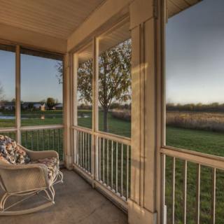 A tranquil screened porch with comfortable seating offering a peaceful view of the natural surroundings during the evening.