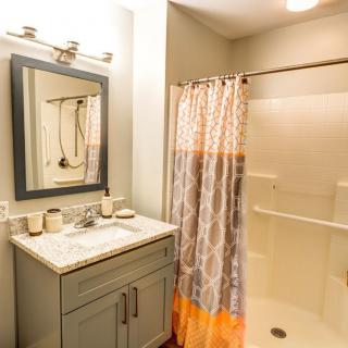 A modern bathroom featuring a vanity with a mirror, sink, and a shower with a patterned curtain.