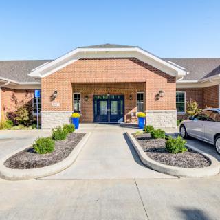 Front view of a residential building with landscaped entrance and parking space.