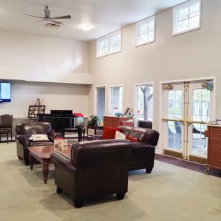 A spacious lounge with leather sofas and a coffee table, featuring ample natural light from large windows.