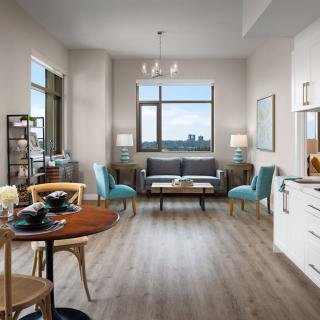 A modern apartment interior featuring a bright living room with stylish furniture, an open kitchen, and a small dining area.