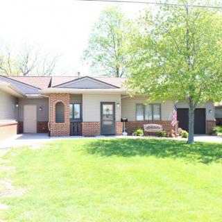 A suburban house with a well-maintained lawn and trees on a sunny day.