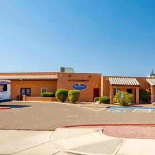 A medical facility with a desert-themed exterior and an adjacent parking lot under a clear blue sky.