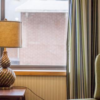 A cozy corner of a room featuring a stylish lamp and striped curtains by the window.