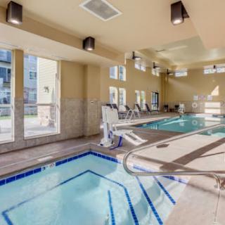 A modern indoor swimming pool area designed for relaxation and fitness, featuring large windows for natural light.