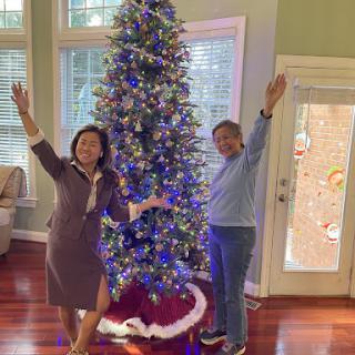 Two people joyfully celebrating the festive season beside a beautifully decorated Christmas tree.