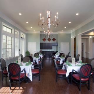 An elegant dining room with neatly arranged tables and chairs under a chandelier.