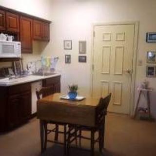 A cozy kitchen with wooden cabinets, a small dining table with chairs, and a microwave.