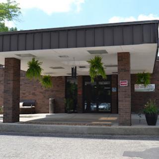 A modern building entrance adorned with hanging plants, inviting visitors in.