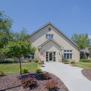 A charming residential house with a neatly landscaped front yard and a paved pathway leading to the entrance.