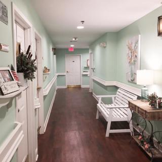 A cozy hallway with mint green walls, a white bench, and decorative artwork.