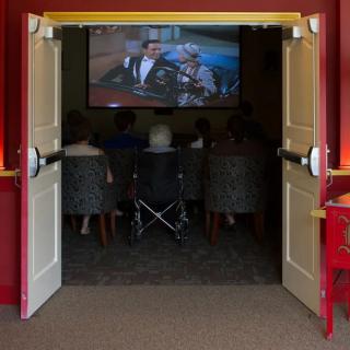 A group of people watching a movie in a small screening room, with one person in a wheelchair.