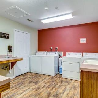 A well-organized laundry room featuring washing machines and dryers against a red accent wall.