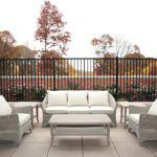 A cozy patio setup with wicker furniture and an autumn backdrop.