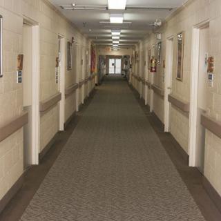 A long, empty hallway with doors on either side, illuminated by fluorescent lights.