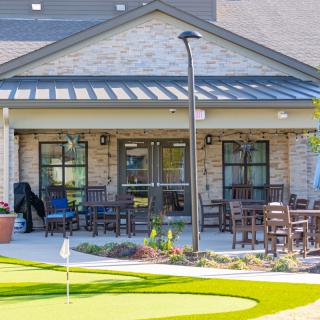 A cozy patio area with outdoor seating and a small putting green in front of a building.