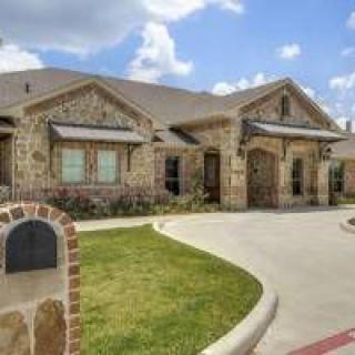 A suburban house with a stone exterior and a curved driveway.