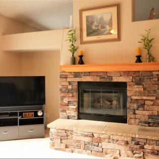 A cozy living room featuring a stone fireplace and a flat-screen television.