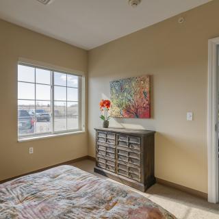 A cozy bedroom with a window, dresser, and colorful decor.