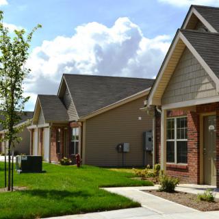 A row of suburban houses with well-kept lawns under a cloudy sky.