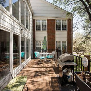 A cozy backyard deck with outdoor seating and a grill next to a house.