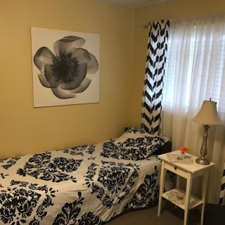 A cozy and stylish bedroom featuring floral artwork and patterned curtains.