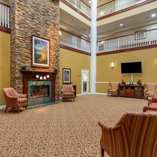 A cozy hotel lobby featuring a stone fireplace, comfortable armchairs, and warm decor.