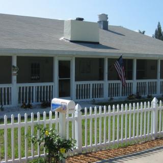A charming house with a white picket fence and an American flag on the porch.