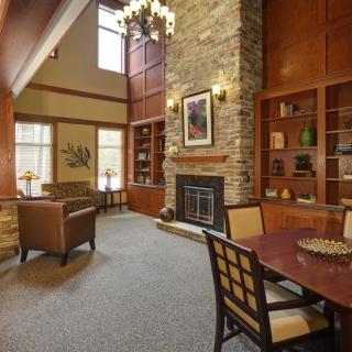 A cozy living room with a fireplace, wooden bookshelves, and comfortable seating.