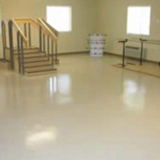An empty room with windows, stairs, and a polished floor.