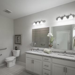 A sleek and modern bathroom with a double vanity, large mirror, and elegant lighting.