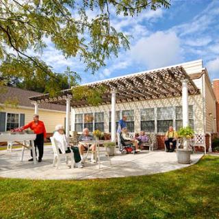 A group of people enjoying a sunny day on a patio with a pergola.